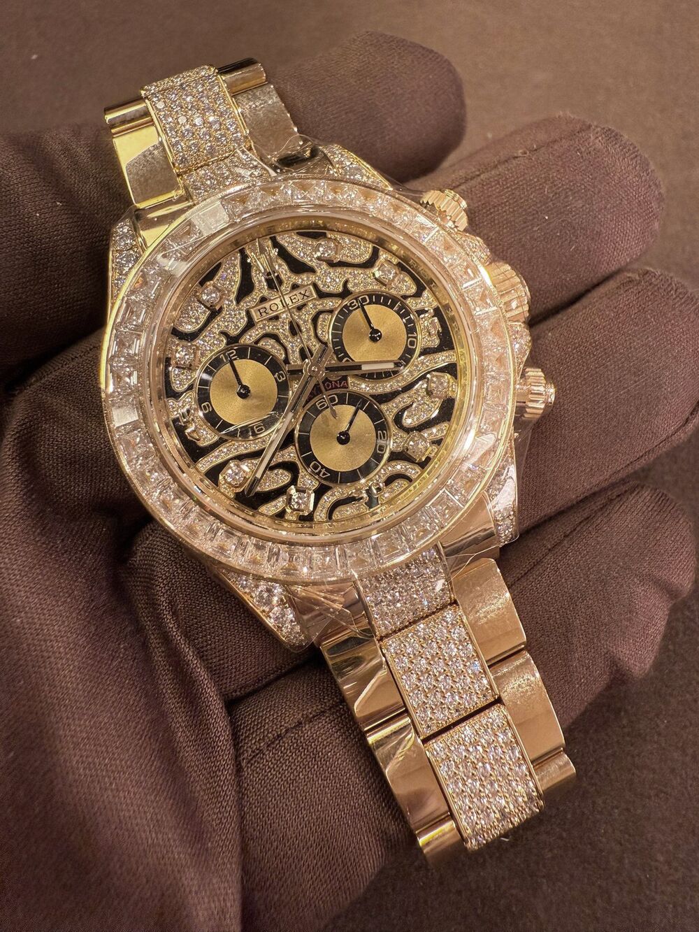 Gem-set rose gold Rolex Daytona held in a gloved hand